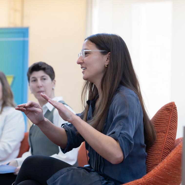 woman sitting in profile speaking with raised hands