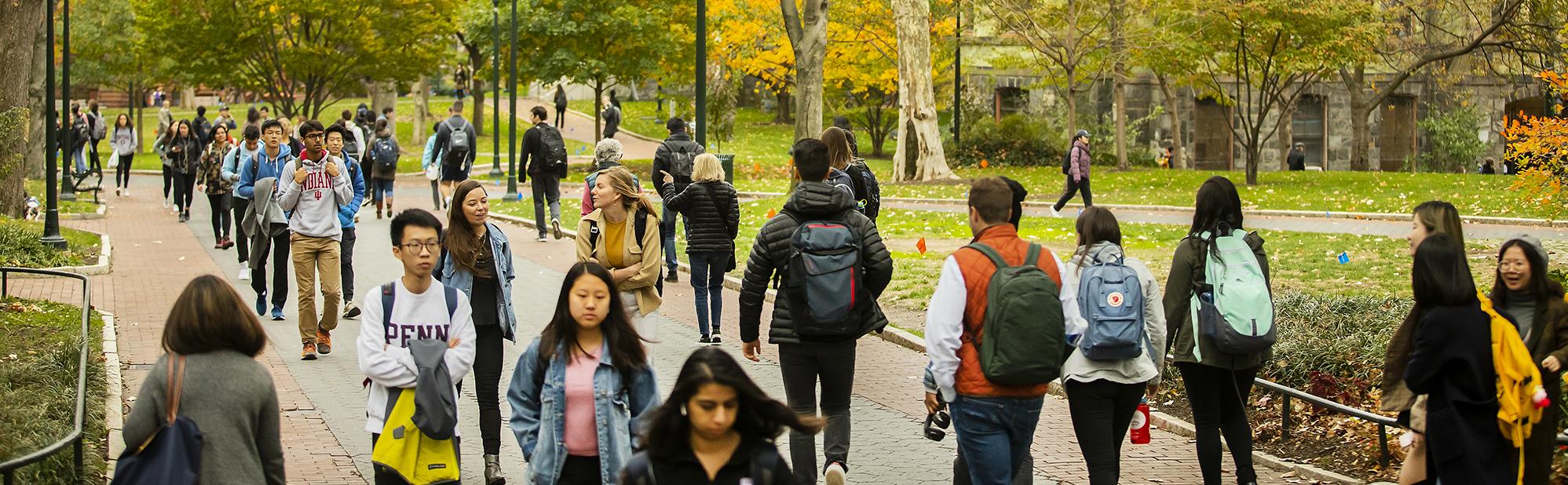 Students walking outdoors with trees with autumn colors
