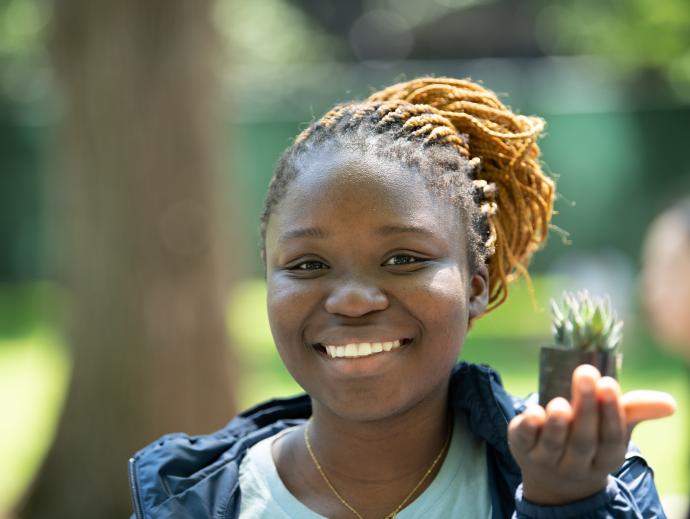 Student holding a plant and smiling