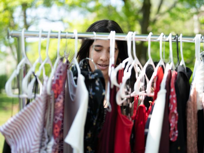in an outdoor setting, a woman is looking through a clothing rack