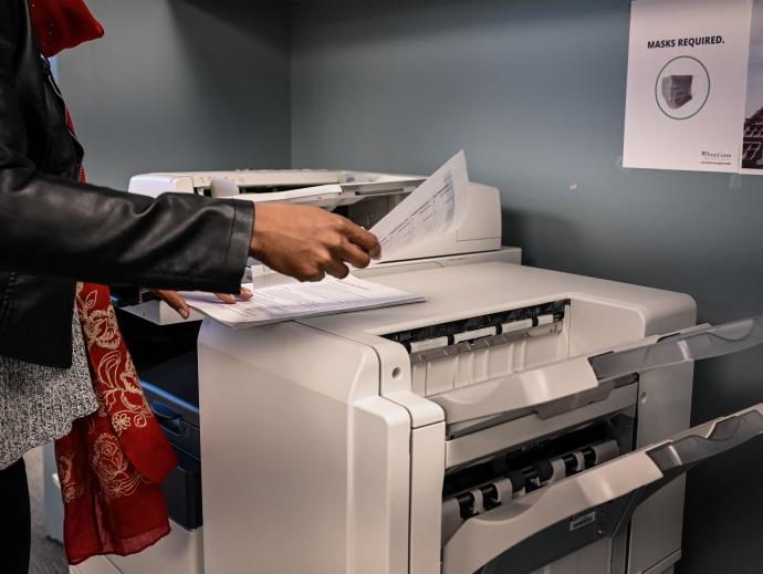 someone standing at a photocopy machine examining some printed pages
