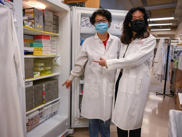 two scientists in white lab coats at freezer