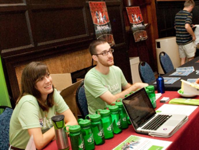 Two Penn Sustainability workers at a table talking to another person