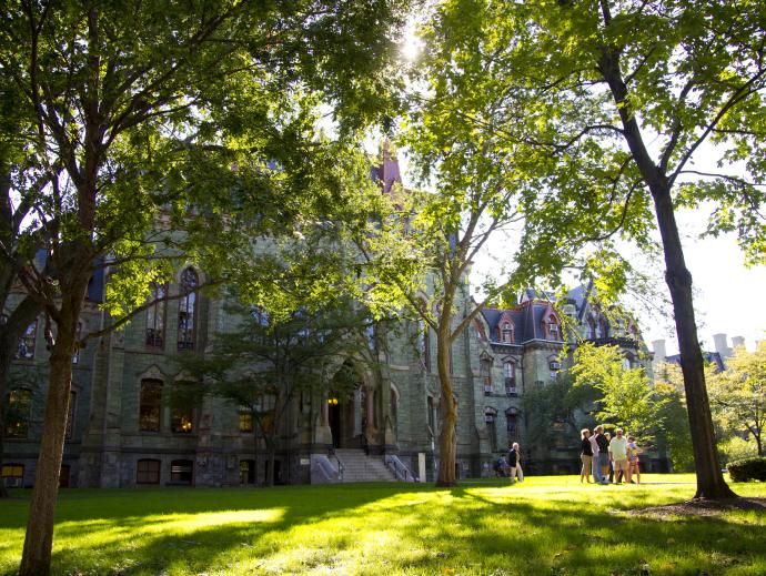 front facade of college hall with a tour group out front