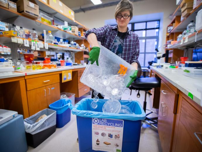 woman in a lab tipping items into larger container