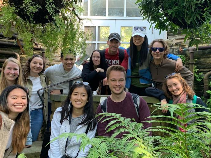 Students smiling in front of a greenhouse