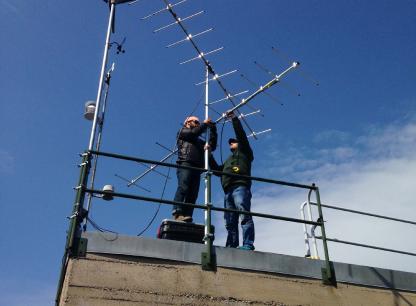 Two people installing wildlife tracking antenna on roof of DRL