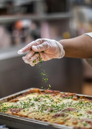 A chef sprinkling herbs on a dish